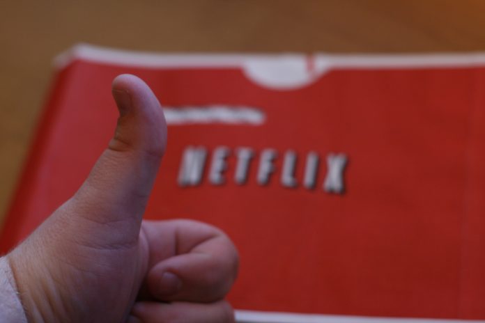 Una mano con el pulgar arriba delante de una hoja que se lee Netflix